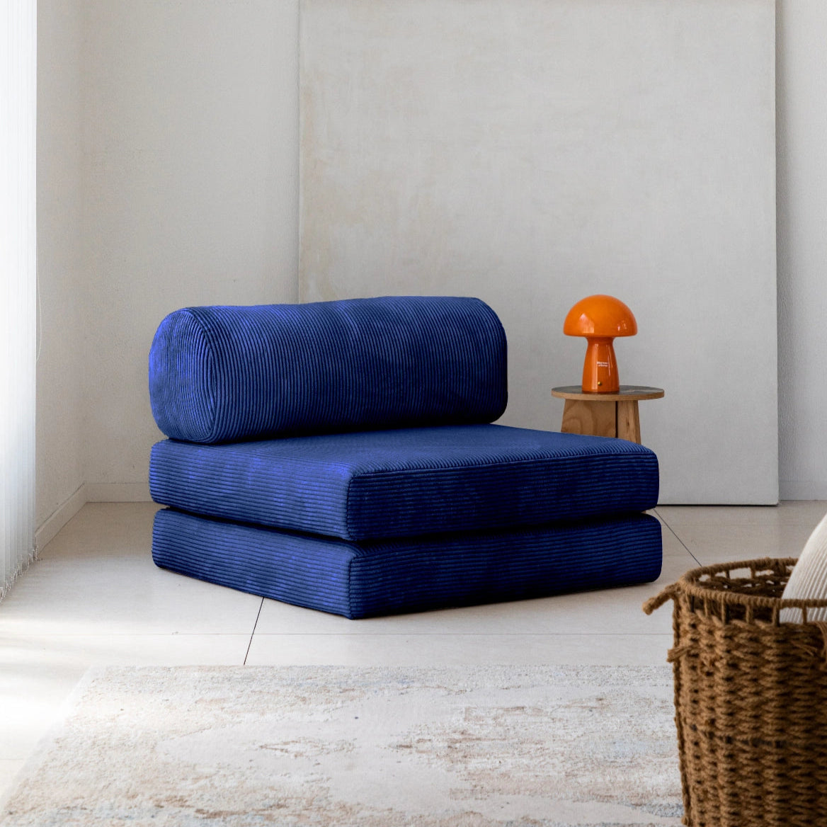 Blue modular chair in a minimalistic room with a white wall and wooden floor.